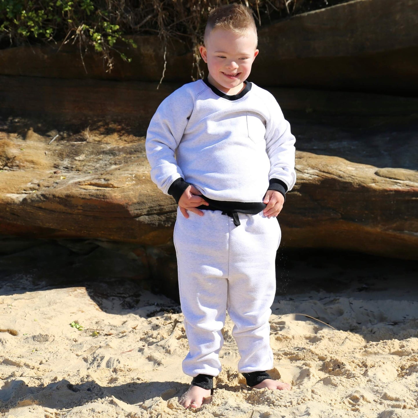 Boy wearing White Marle trackpant featuring black contrast waistband, hem cuffs and drawcord, side pockets. Ethically made in Australia with cotton blend cosy and warm fleece