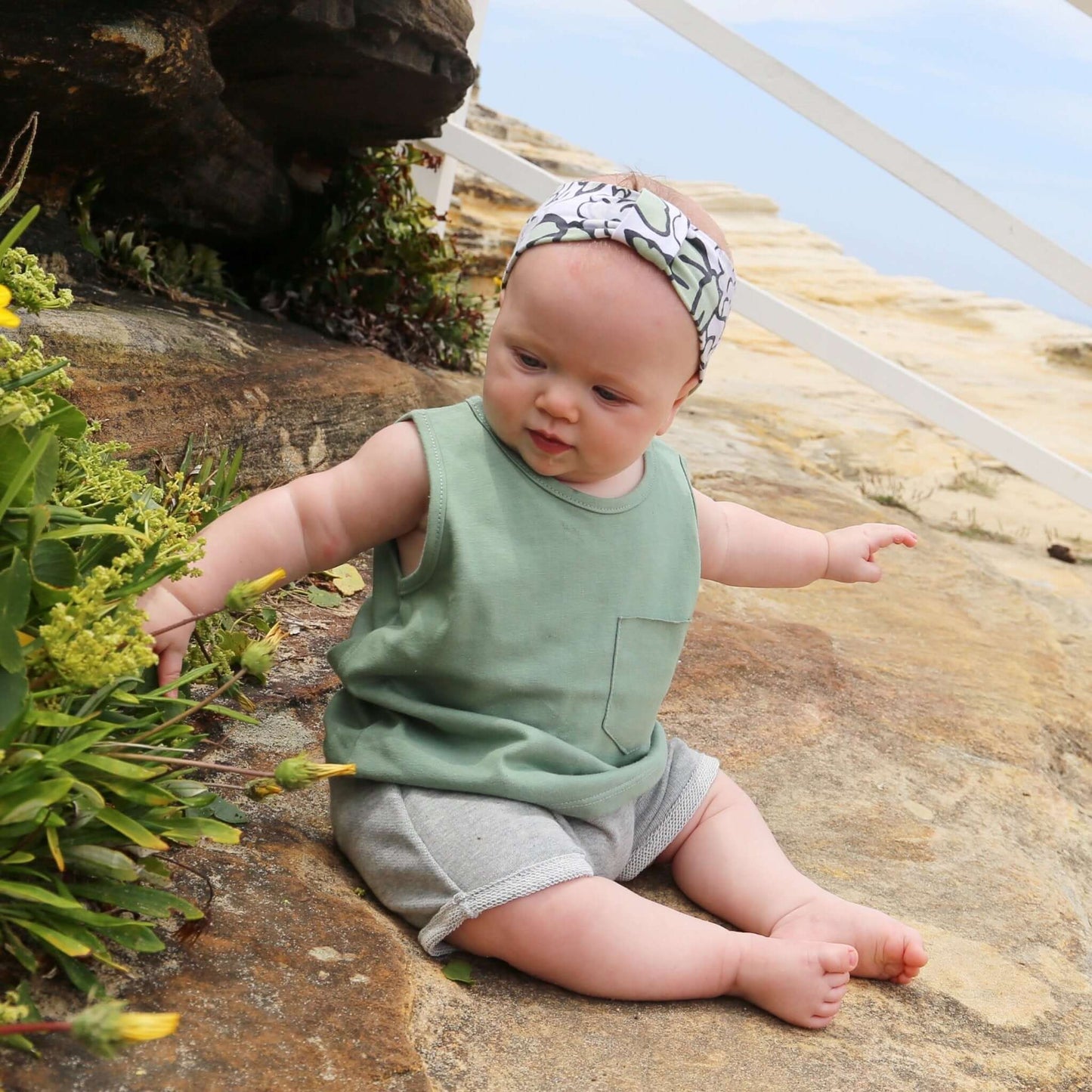 baby girl wearing sage colour singlet with front pocket. Ethically made in australia with 100% cotton jersey