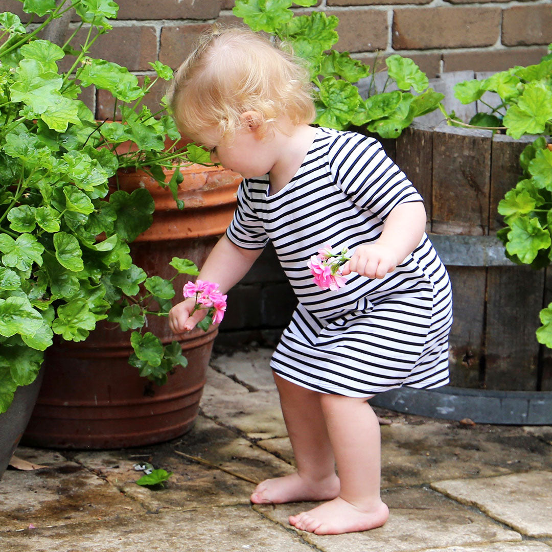 toddler girl wearing white with black stripe casual dress featuring 3/4 sleeves. Ethically made in australia with a cotton/elastane jersey fabric. Dress length sits at knee.