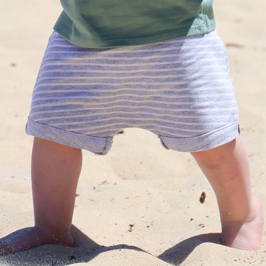 Toddler wearing grey jersey drop crotch shorts with white contrast stripe.  Ethically made in Australia with a soft stretch jersey fabric