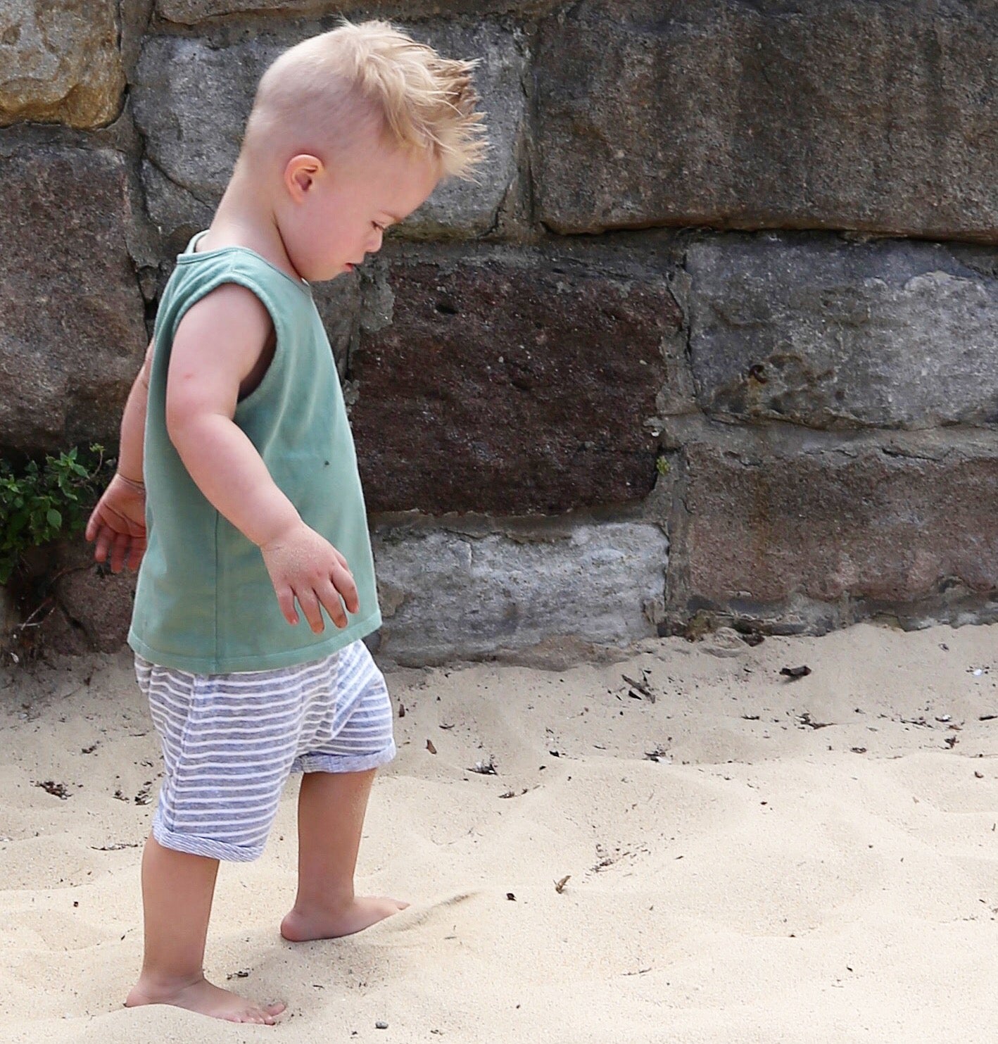 Toddler wearing grey jersey drop crotch shorts with white contrast stripe.  Ethically made in Australia with a soft stretch jersey fabric